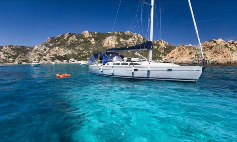 A yacht at anchor in turquoise water off Sardinia