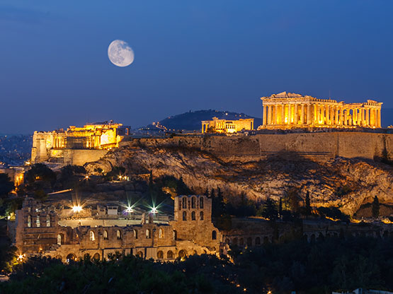 Parthenon and Herodium construction in Acropolis Hill in Athens, Greece shot in blue hour with moon in the sky