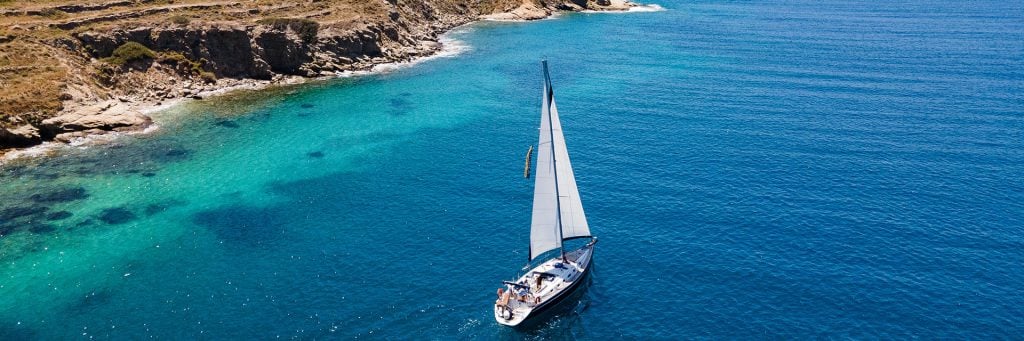 A yacht sailing in turquoise water off Ios in the Cyclades