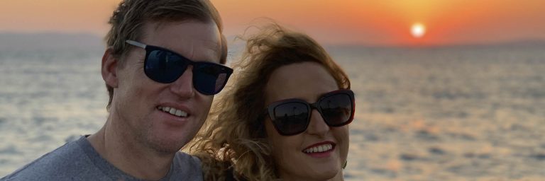 Two AHOY guests smiling on board at sunset