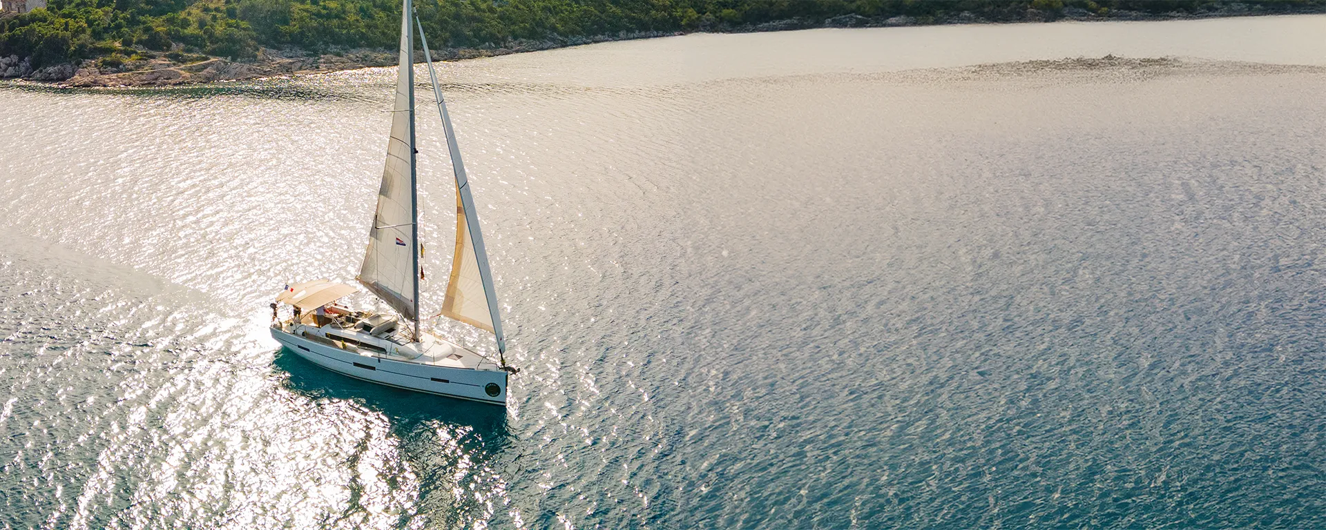 A Dufour 412 Grand Large sailing across a calm bay