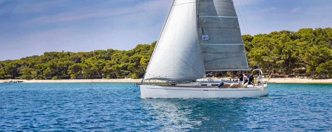 A Seafarer training yacht sailing past a pine-covered shore on the Dalmatian coast, RYA training centre Croatia