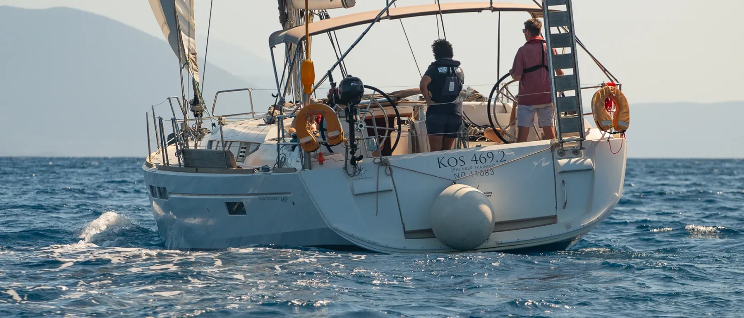 Crew in the cockpit of a Seafarer Sun Odyssey 469 training yacht under sail off the Greek coast