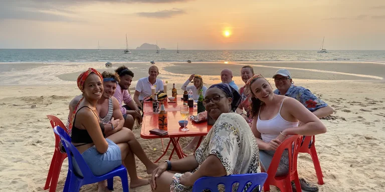 AHOY guests at a table on a Thai beach at sunset