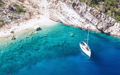 A yacht anchored near stunning rocky cliffs and clear blue water, highlighting the beauty of yacht charter preparation