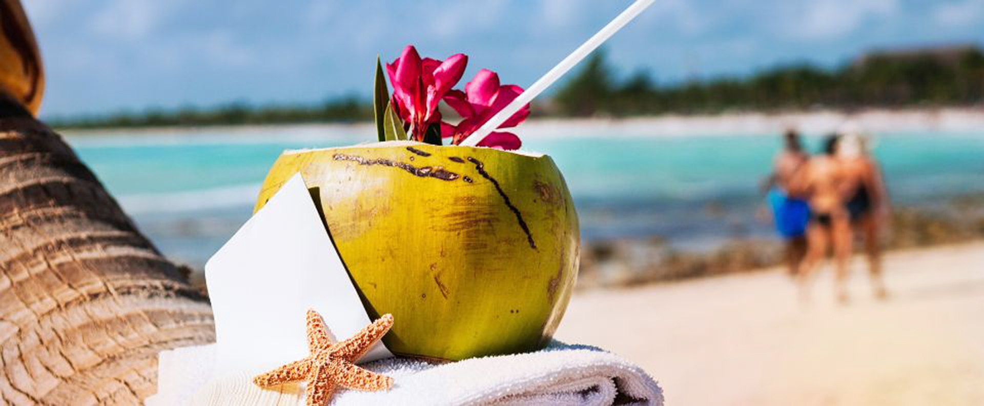 A fresh coconut drink adorned with flowers on a sandy Caribbean beach, a perfect moment on Caribbean yacht charters