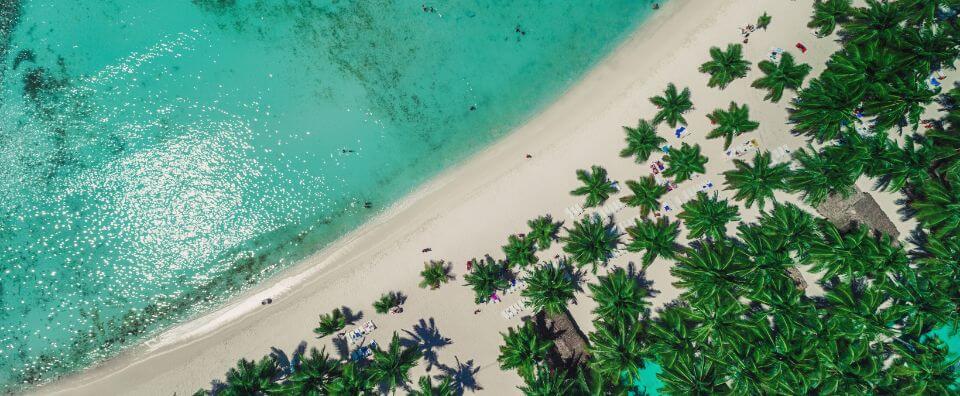 A stunning aerial view of a tropical beach, turquoise waters, and palm trees, perfect for Caribbean yacht charters