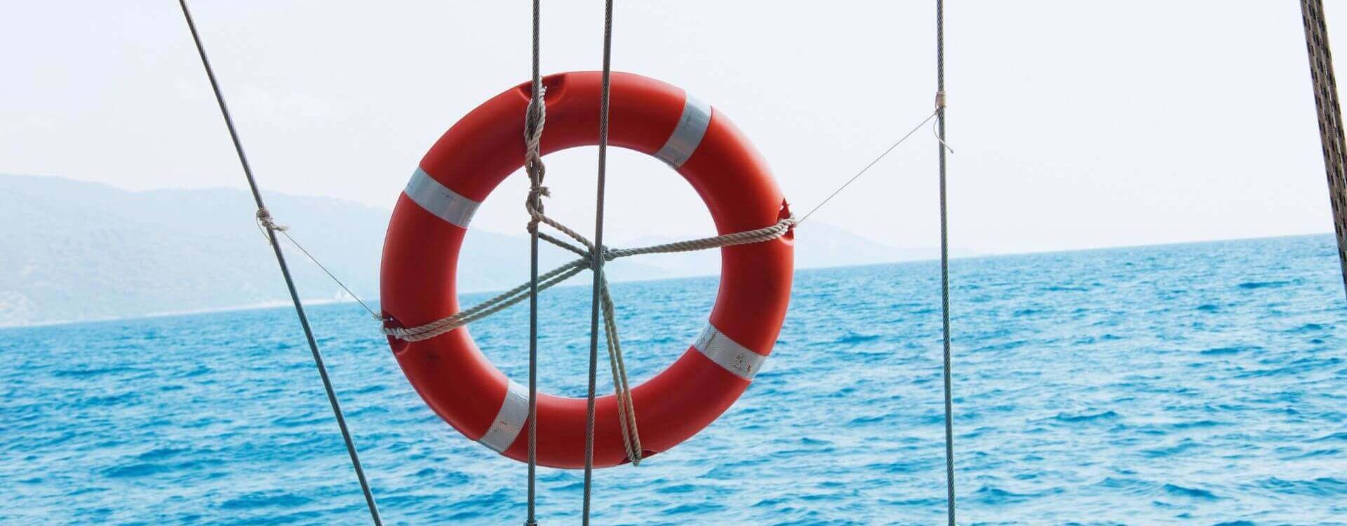 A bright orange life ring secured on a yacht against a backdrop of calm blue sea, highlighting yacht charter safety essentials.