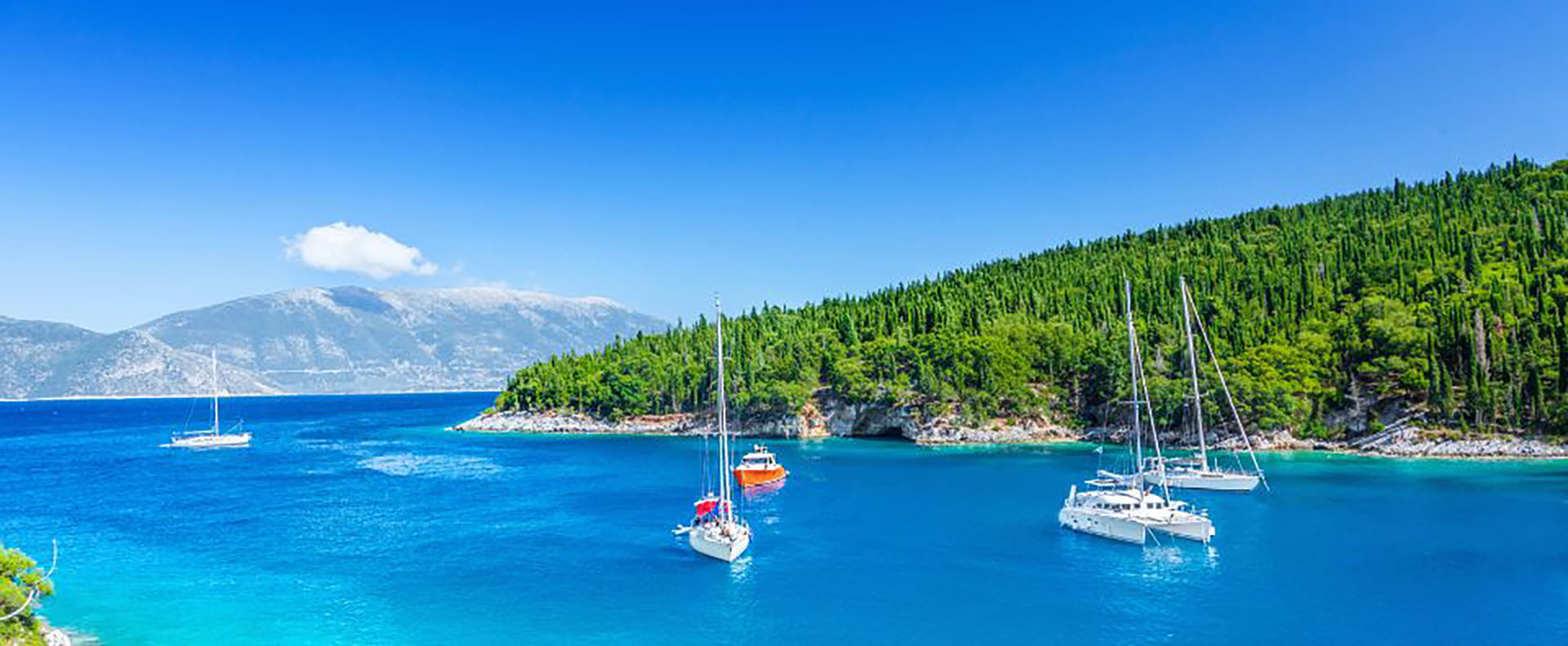 Yachts anchored in the turquoise waters of Kefalonia, surrounded by lush green hills, ideal for Greek island sailing adventures.