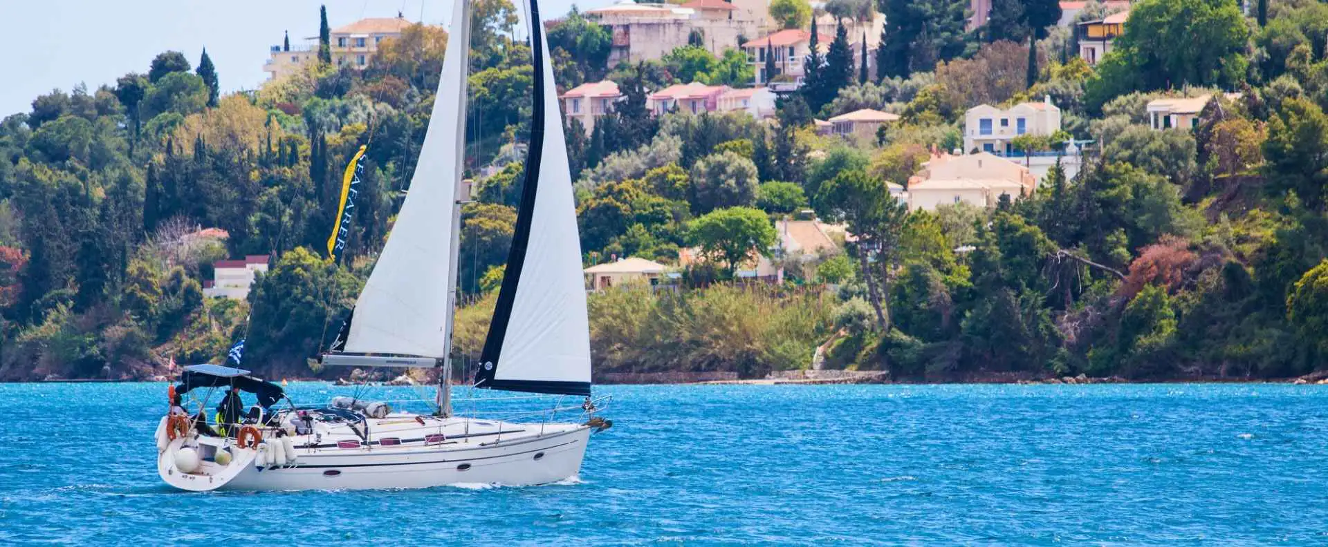 A white sailboat near a Greek coastal town, where sailors train on an RYA course.