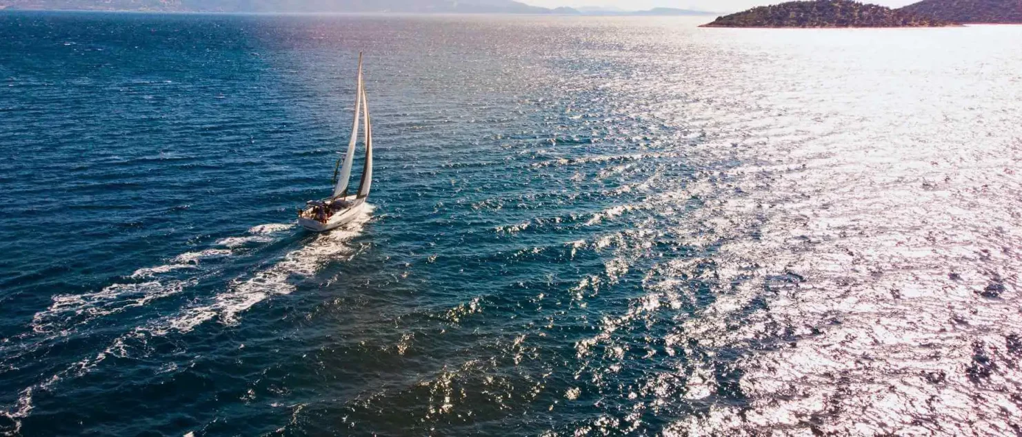 A yacht sails across the open sea, offering hands-on experience in an RYA sailing course