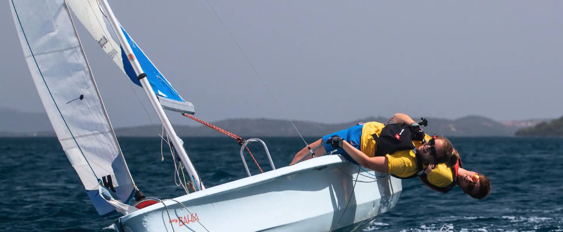 Two sailing trainees demonstrating hiking techniques on a dinghy boat at Seafarer Academy