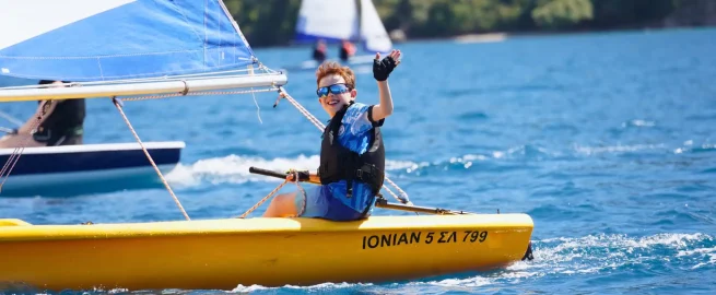 A child at the helm of a dinghy during a sailing lesson