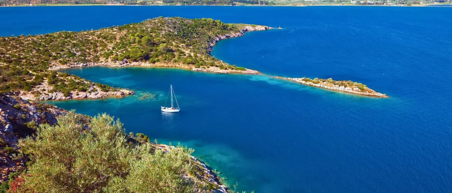 A sailing yacht anchored in a secluded Greek bay, essential sailing gear packed for a smooth trip