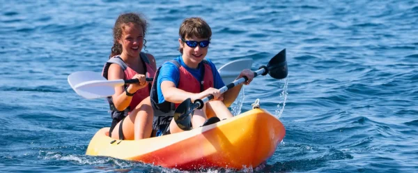 Two children kayaking in clear water
