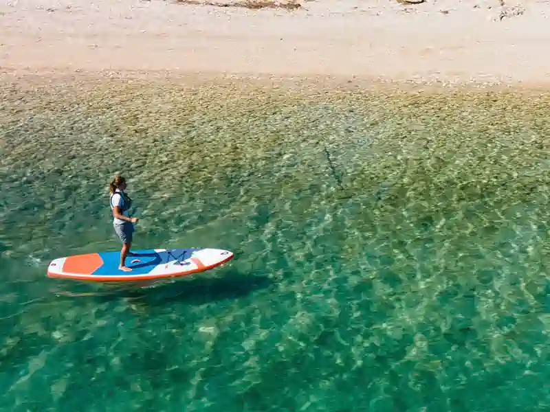 Paddleboarder on crystal-clear waters near Nikiana Beach Club in Greece – Seafarer Sailing holidays