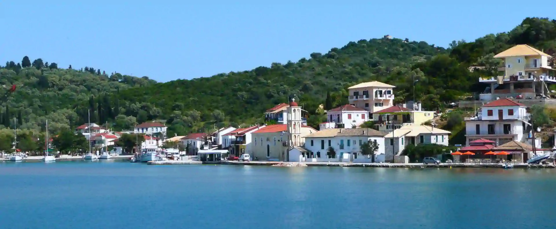 Peaceful harbour village with yachts moored along the waterfront in the Ionian Islands