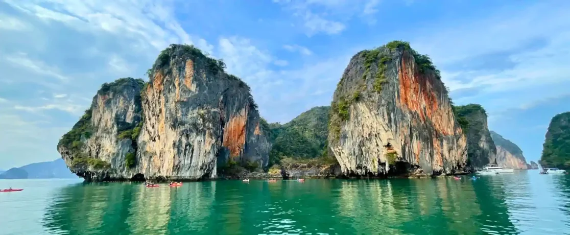 Kayakers beneath towering limestone karsts in Phang Nga Bay
