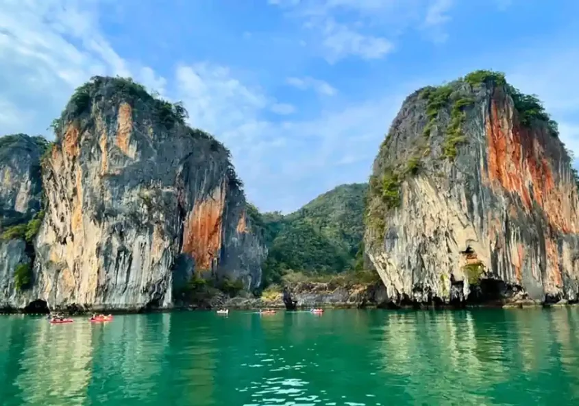 Kayakers glide beneath towering limestone karsts in Phang Nga Bay, Thailand