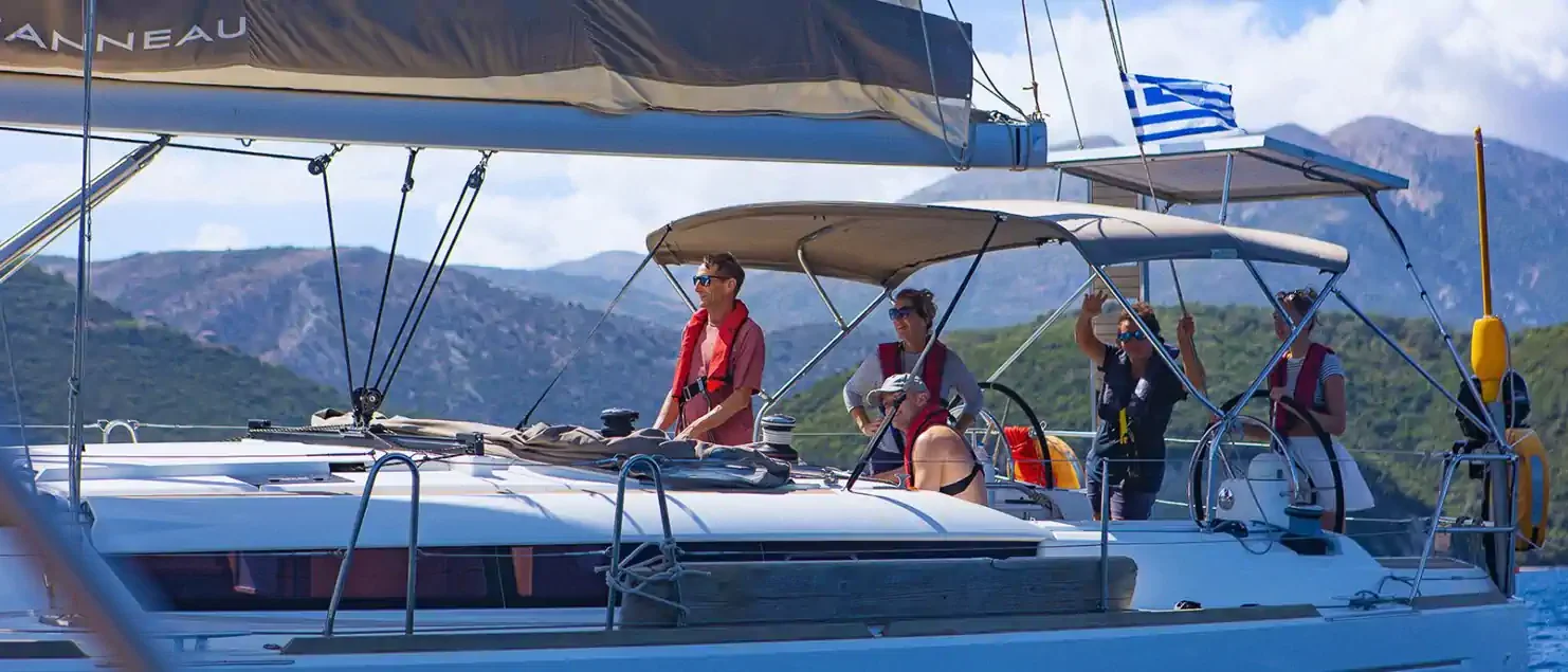 Crew sailing a charter yacht with a battened mainsail and lazy bag on the boom.