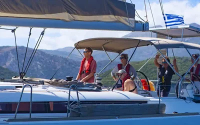Crew sailing a charter yacht with a battened mainsail and lazy bag on the boom.