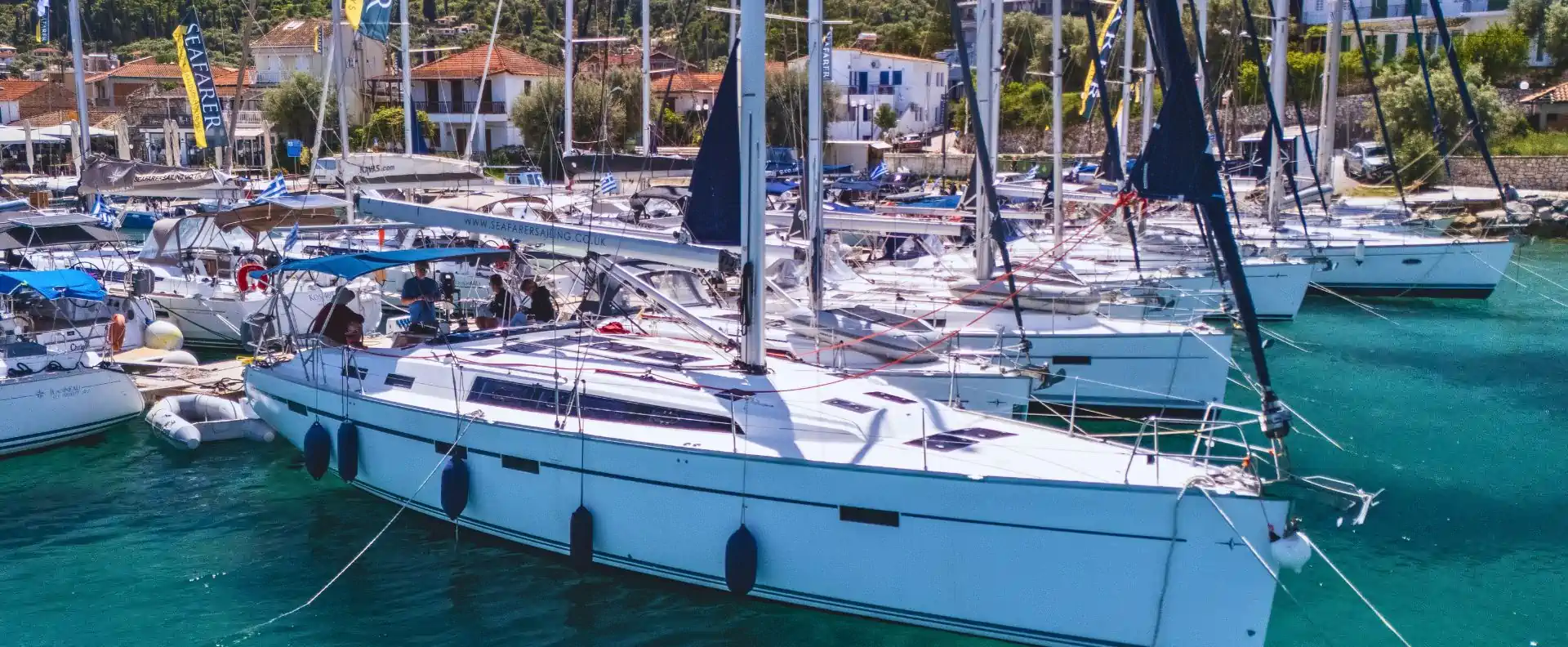 Charter yachts moored in a Greek marina, showing different mainsail types.