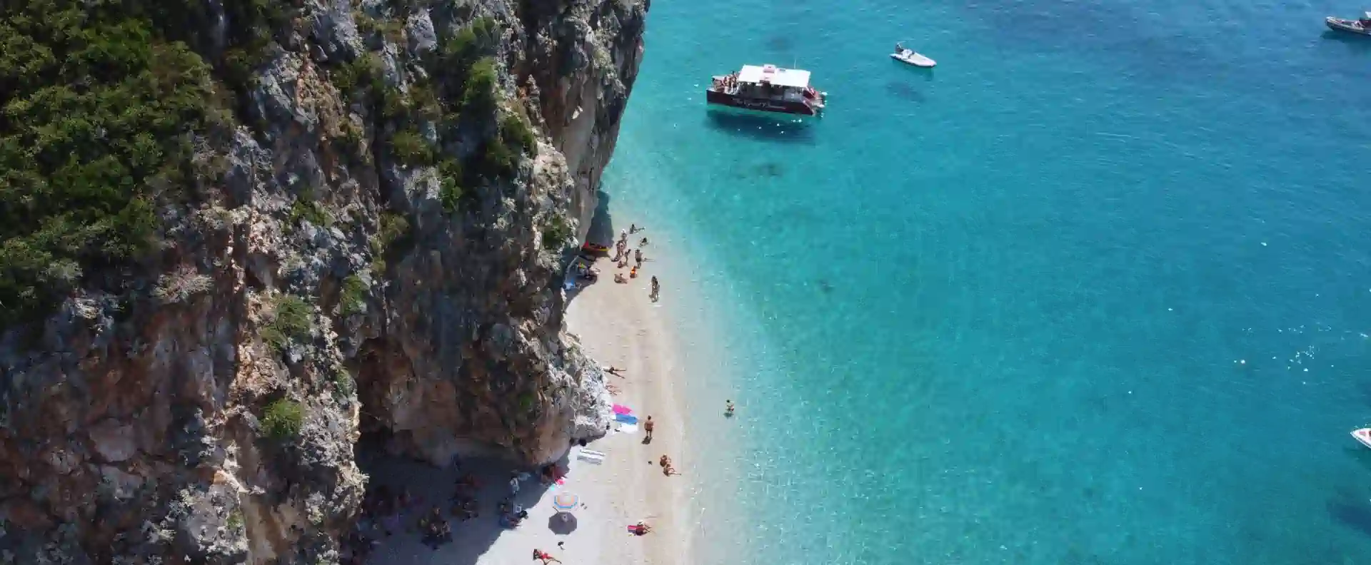 Himarë cliff cove with turquoise water and anchored boats on the milebuilder sailing route