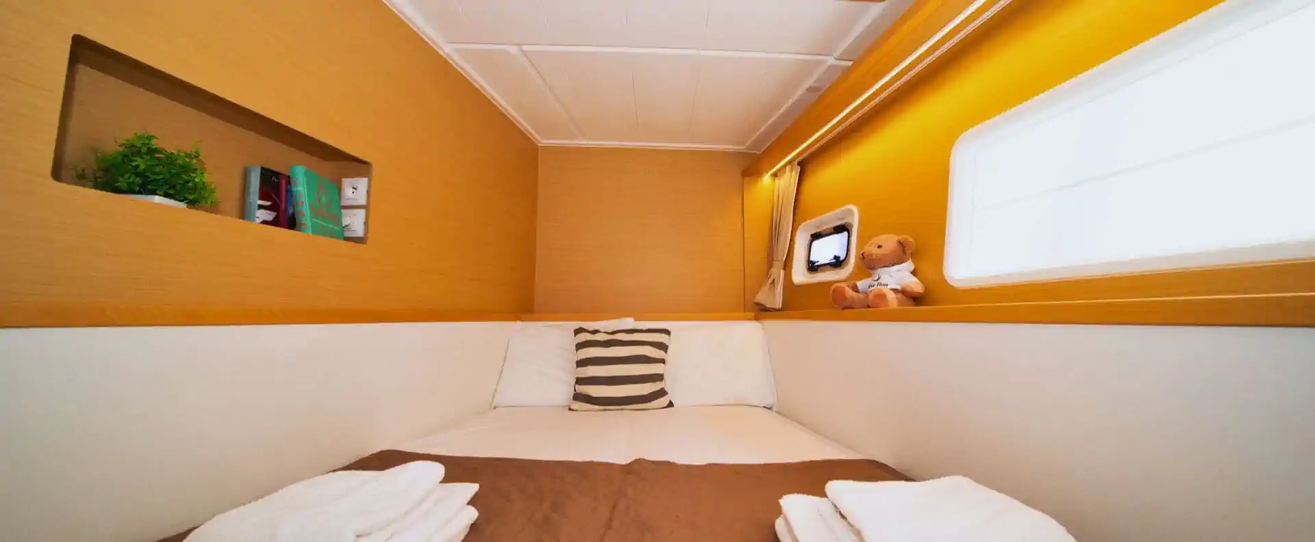 Double cabin inside the Lagoon 400 sailing catamaran with cosy lighting, soft bedding, and a view through the port window.