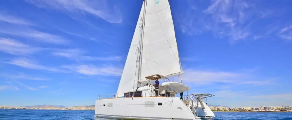 Lagoon 400 sailing catamaran cruising under full sail on calm blue waters off the Greek coast.