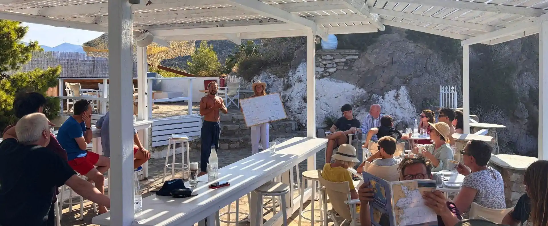 Skipper briefing during a Corinth Flotilla sailing route in Greece, with guests gathered ashore.