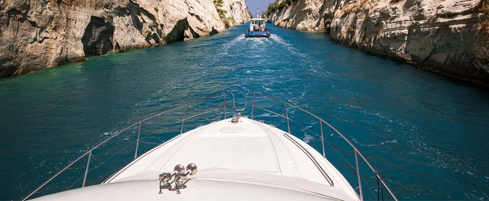 Sailing through the Corinth Canal in Greece, with steep limestone walls rising on both sides.