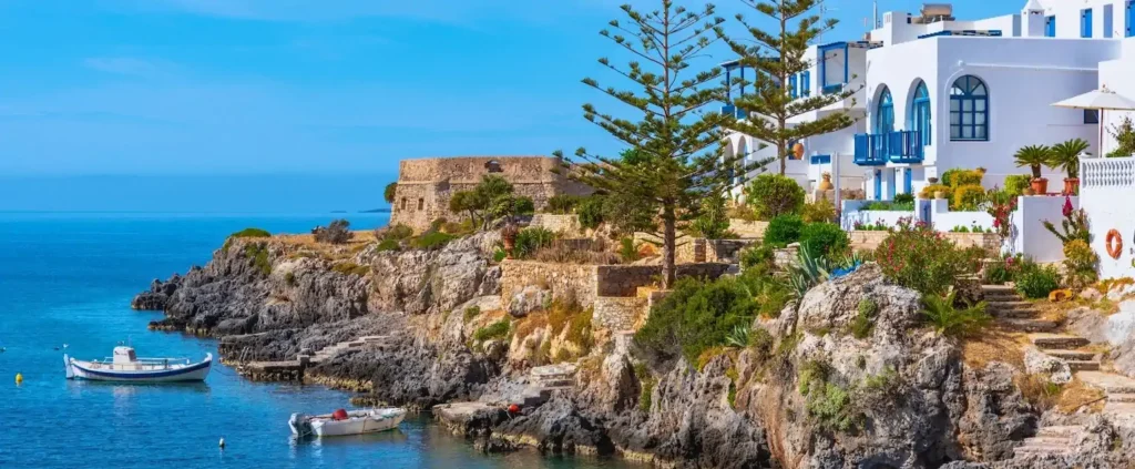 Greek island coastline with whitewashed buildings and moored boats, Greece sailing holiday