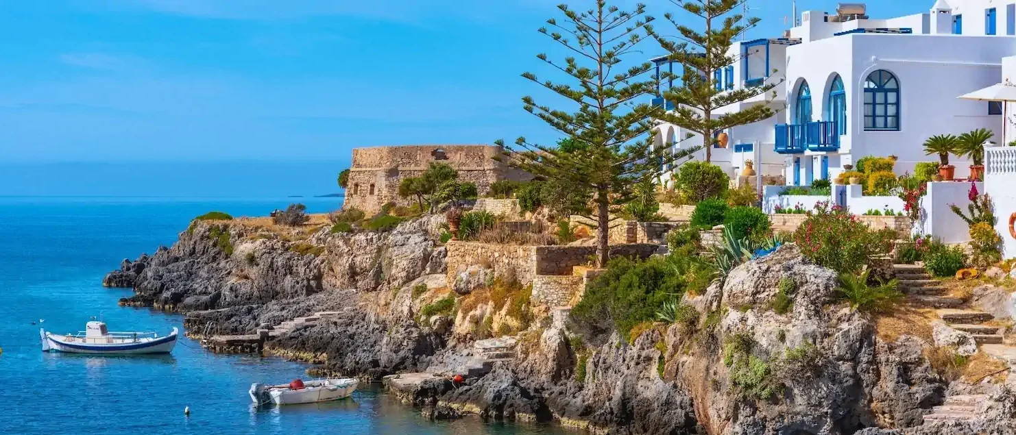 Greek island coastline with whitewashed buildings and moored boats, Greece sailing holiday