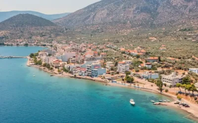 Corinth Canal sailing route coast Aerial view of a coastal town on the Corinth Canal sailing route, surrounded by turquoise water and mountains