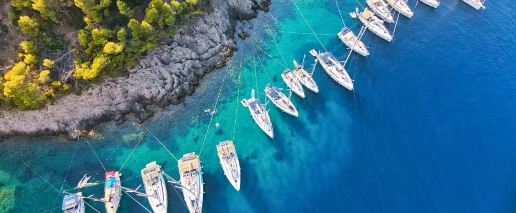 Aerial view of flotilla yachts moored in clear blue water while sailing around Kefalonia, Assos