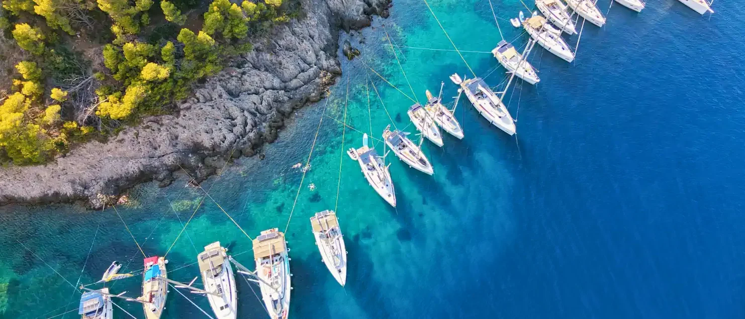 Aerial view of flotilla yachts moored in clear blue water while sailing around Kefalonia, Assos