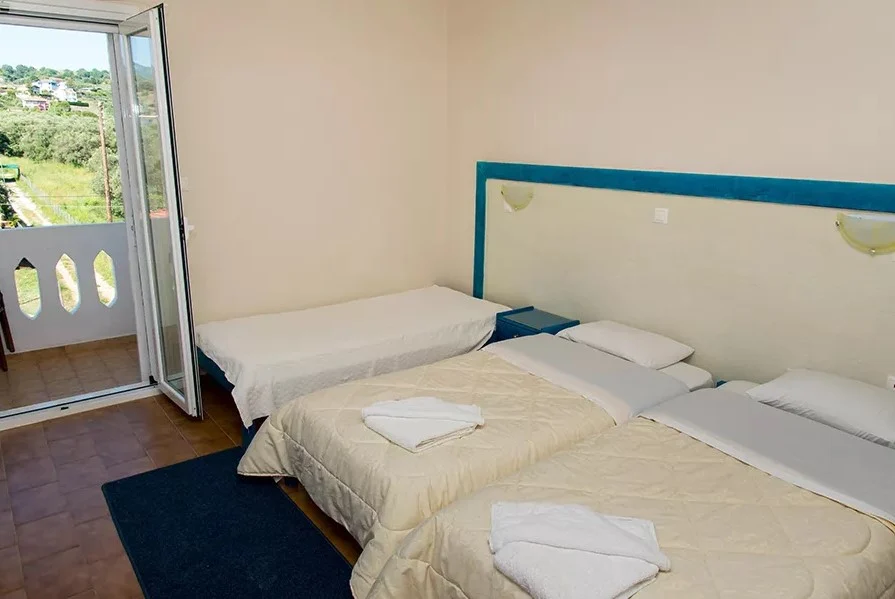 Triple Mountain View Room at Poseidon Beach Club, with three single beds and a balcony looking out over green hills