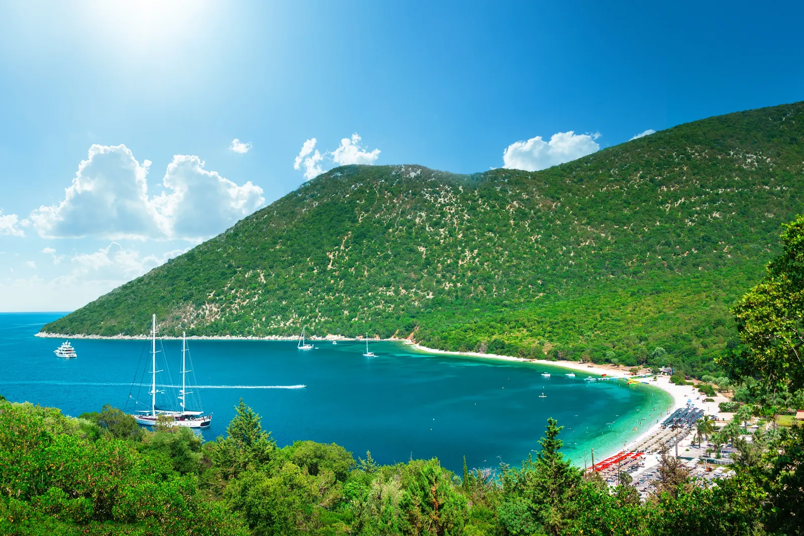 Yachts at anchor in the turquoise bay of Antisamos beach, Kefalonia, below green hills
