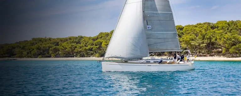 A training yacht under sail off a beach on the Dalmatian coast