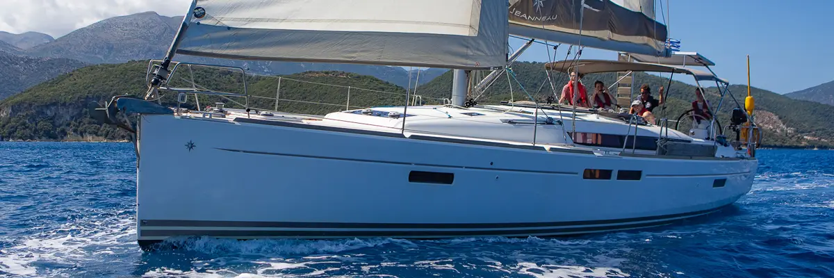 A crew sailing a Seafarer yacht along the green Ionian coast, as on a flotilla holiday